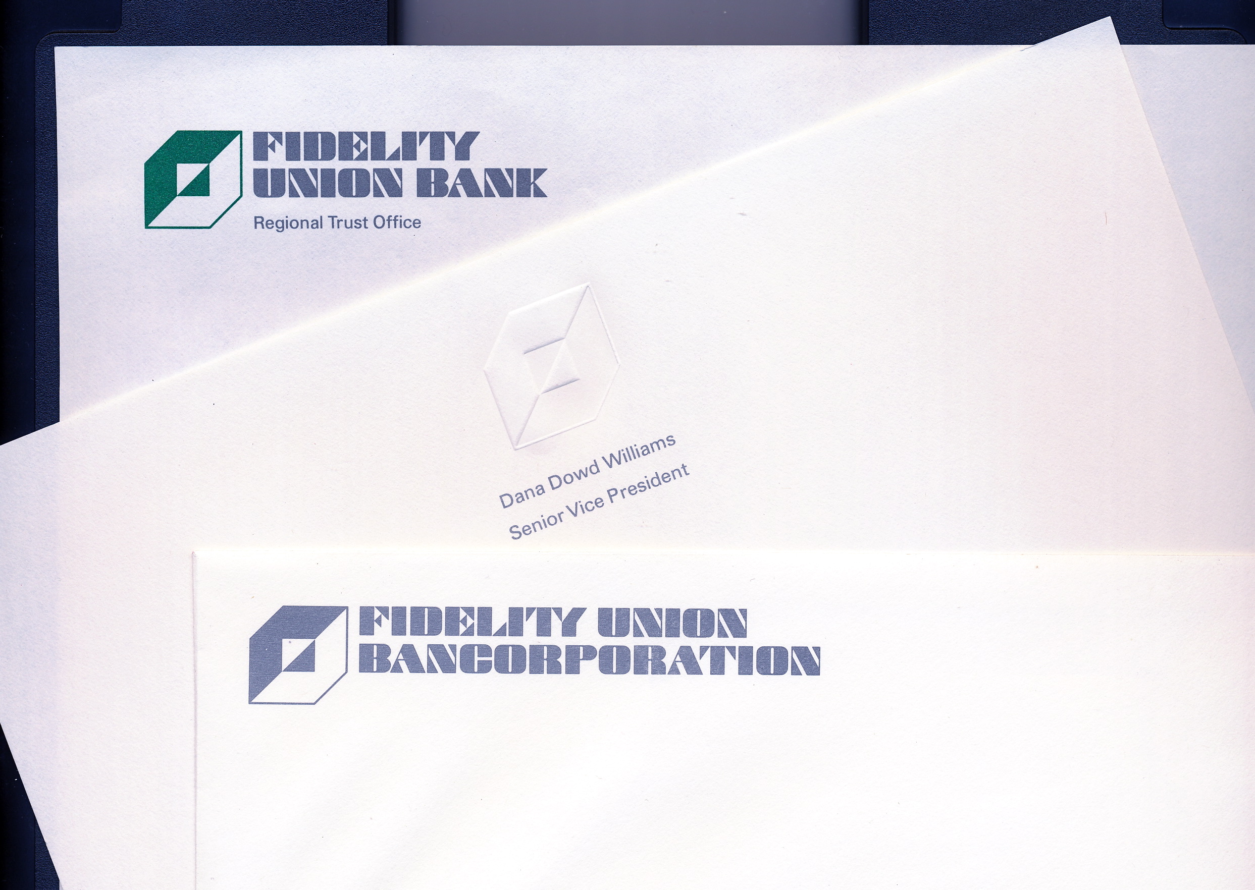 Logo and typface applications atop several pieces of paper.  Three different designs for the new letterhead.