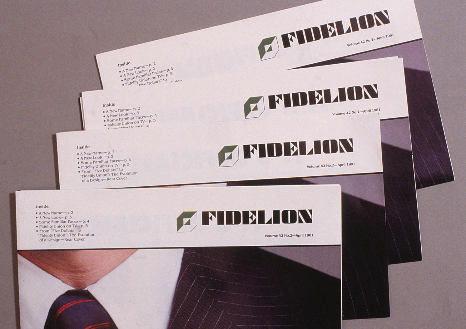 Logo and typface applications on a pile of the Fidelion monthly newsletter.
