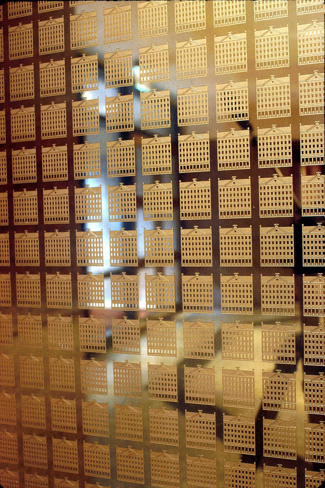 Etched bronze elevator doors featuring a repetitivive logo pattern.