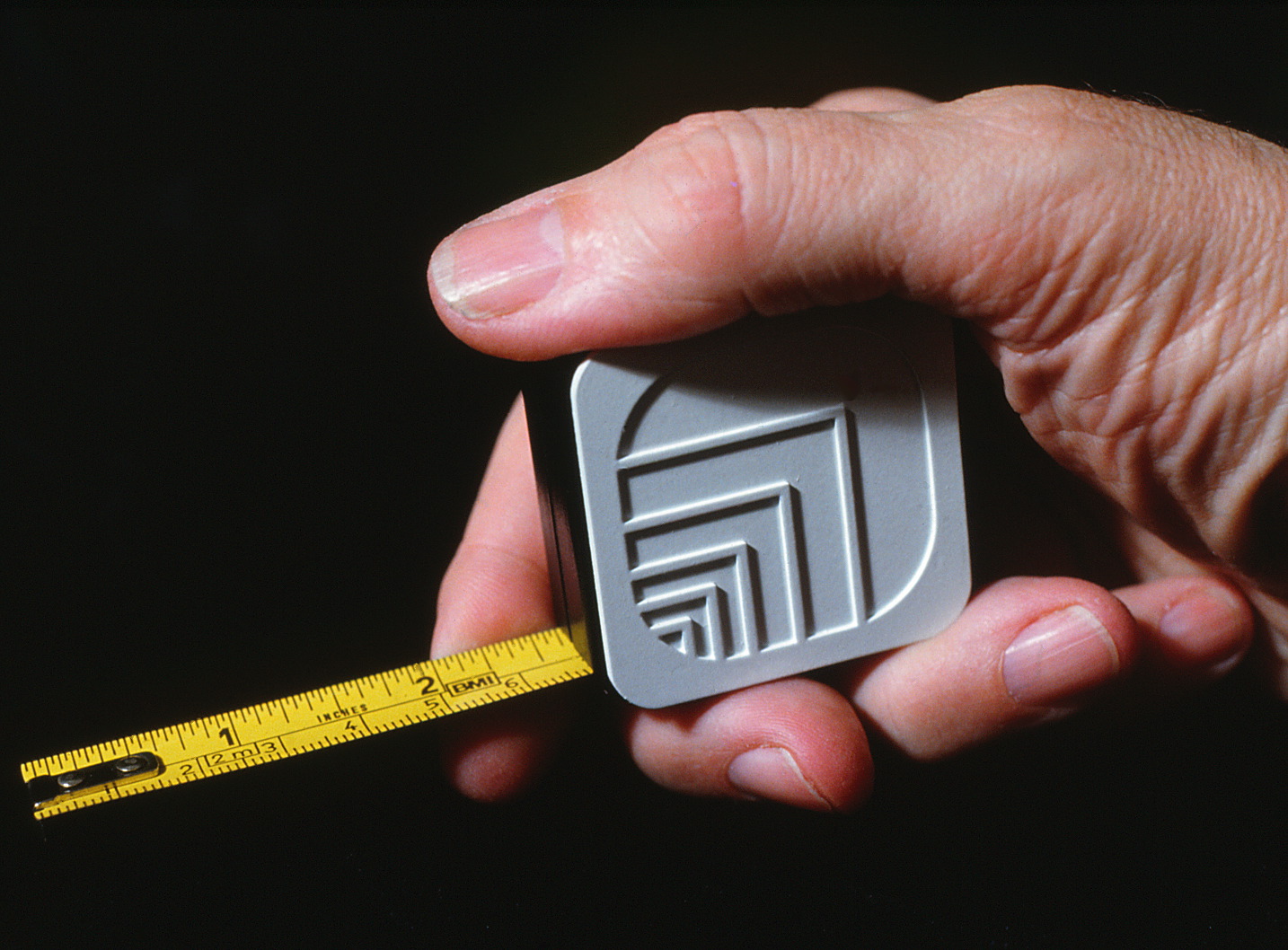 Hand holding a tape measure featuring Oxford logo.