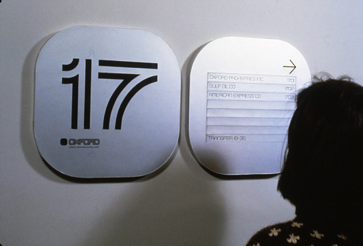 A woman ooking at rounded rectangular signs on a wall.
