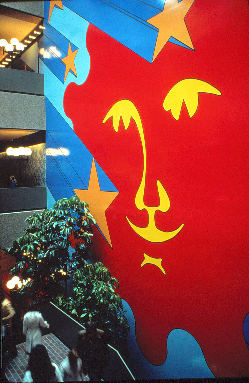 Large smiling face mural painted on a temporary wall during construction.