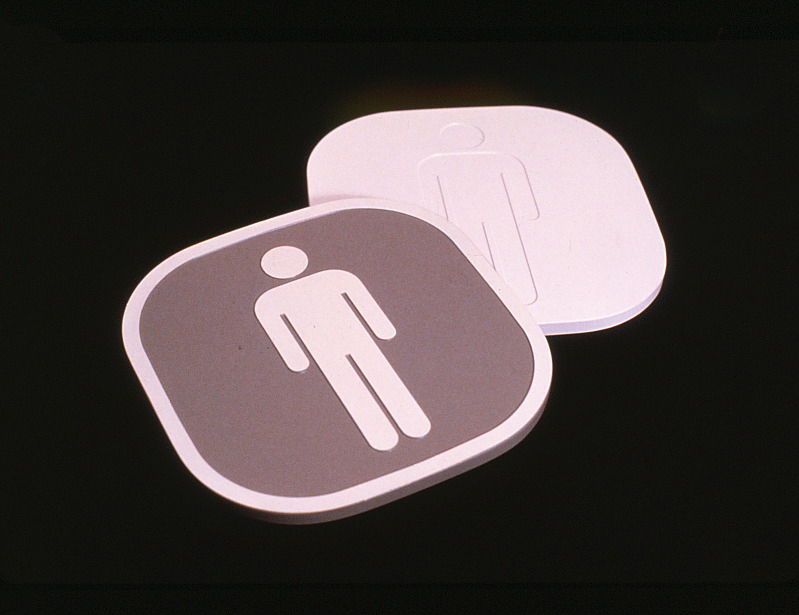 Closeup of pictogram signs featuring two identifying the mens room.