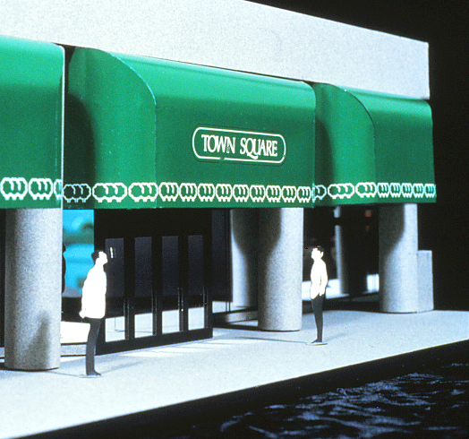 Model of the canopy into the office and retail complex featuring logo and script.