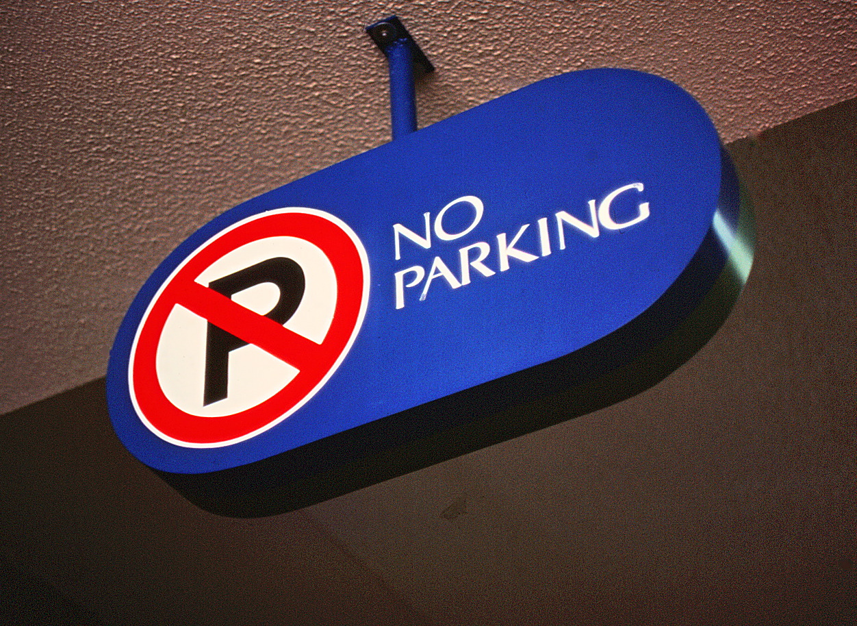 Closeup of a no parking sign mounted to a ceiling.