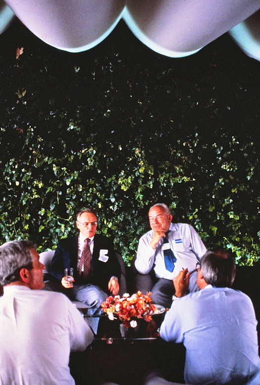Two men seated and talking in front of the Ivy Wall.